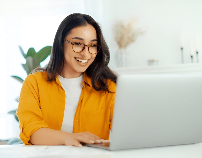 Happy woman using a laptop at home, symbolizing the convenience and efficiency of Answer Engine Optimization services for digital success.