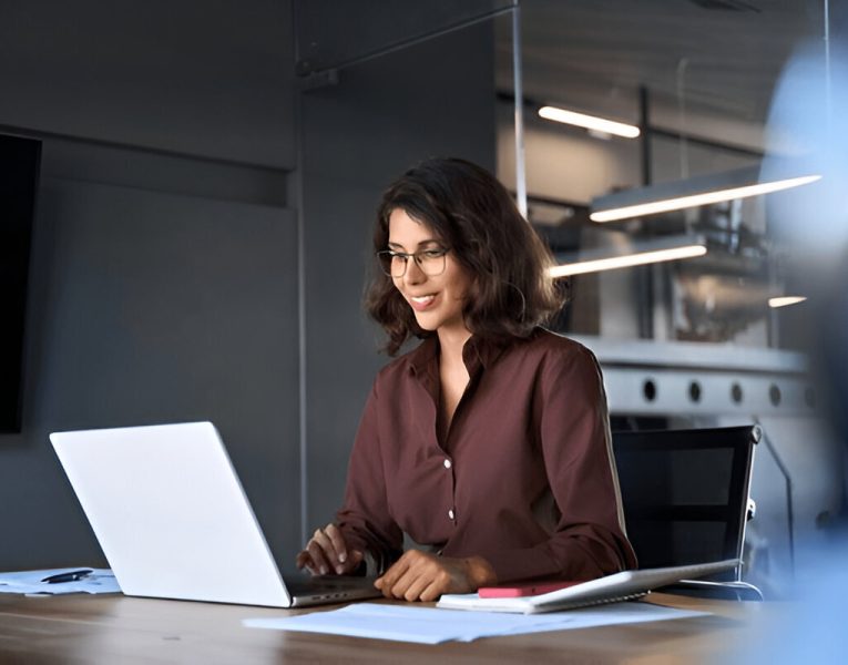 Professional woman working on a laptop in a modern office, representing the impact of Answer Engine Optimization services in business growth.